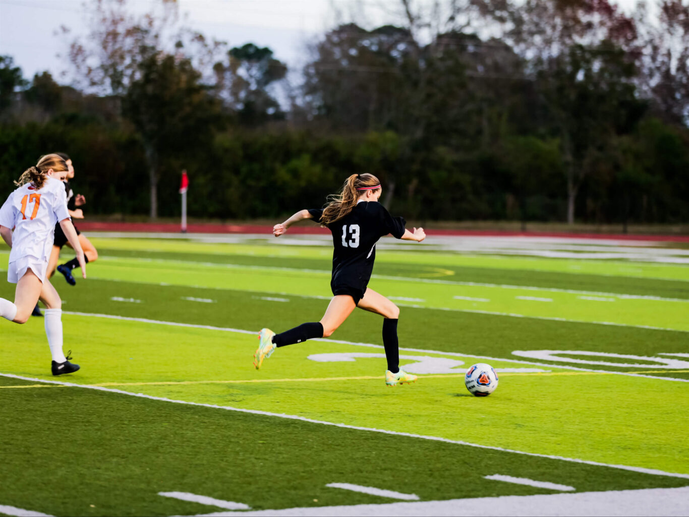 Two girls passionately playing soccer on a large field.