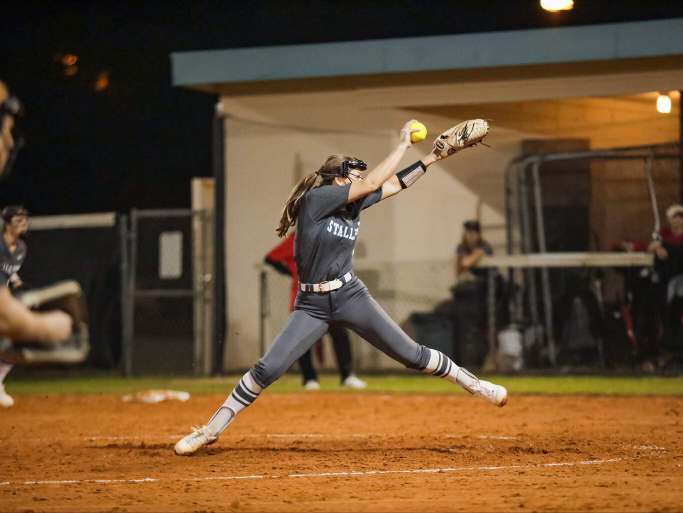 A girls' softball player swinging at a ball during a game.