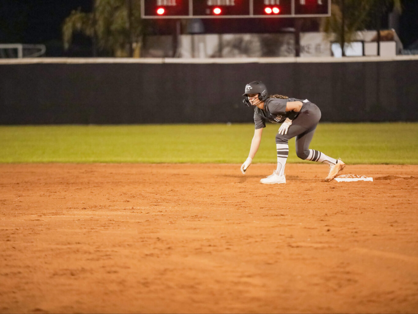 A softball player, preferably a girl, is reaching for a base on a dirt field.