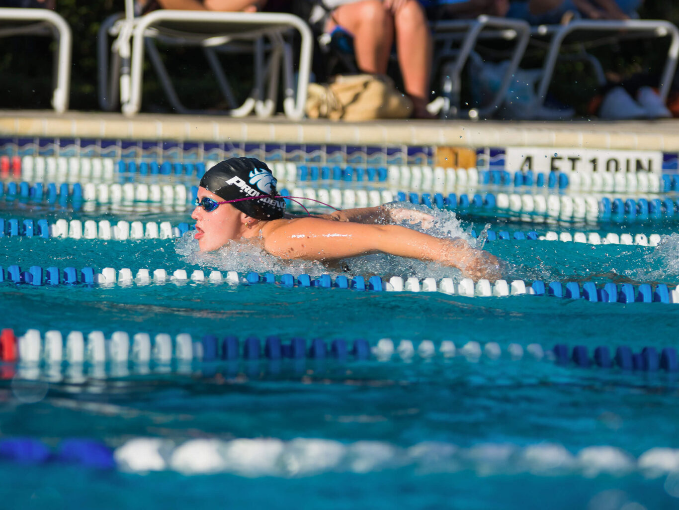 A girl is swimming in a pool.