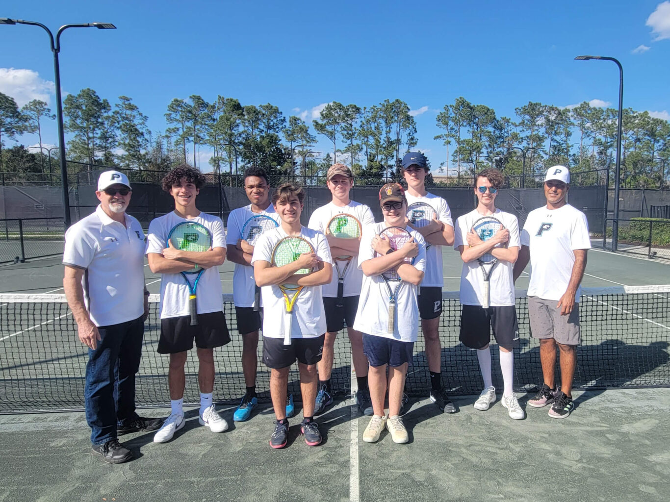 A group of young boys posing for a picture on a tennis court.