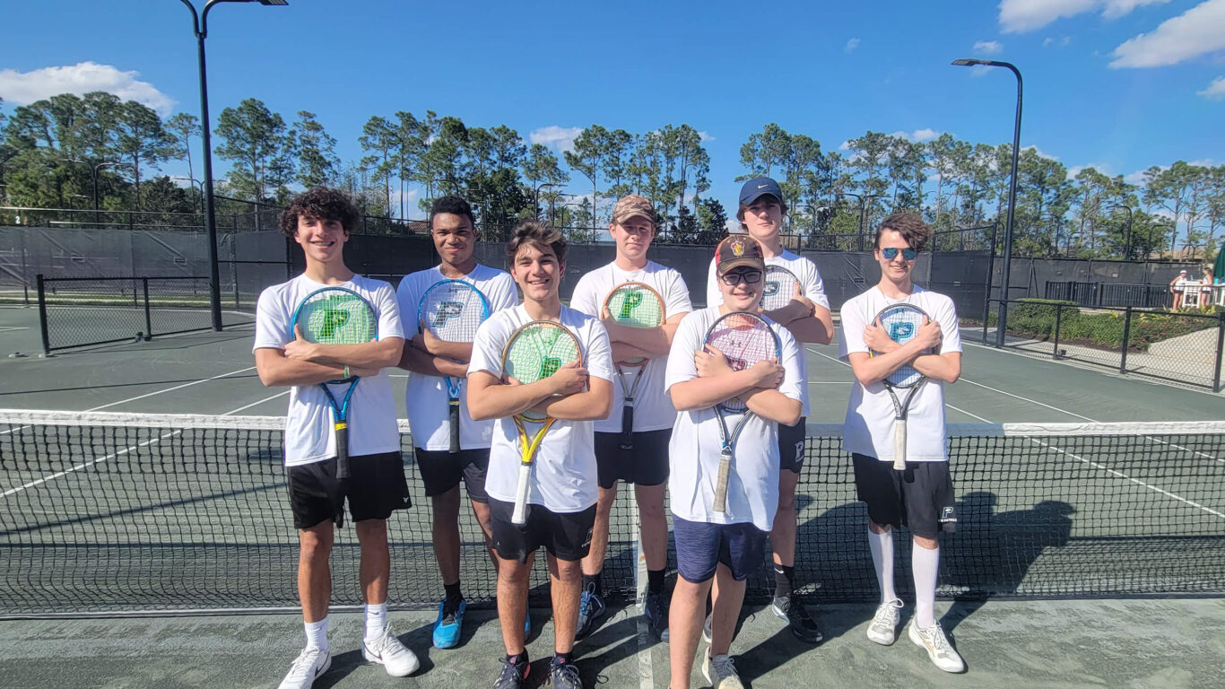 A group of boys posing for a picture on a tennis court.