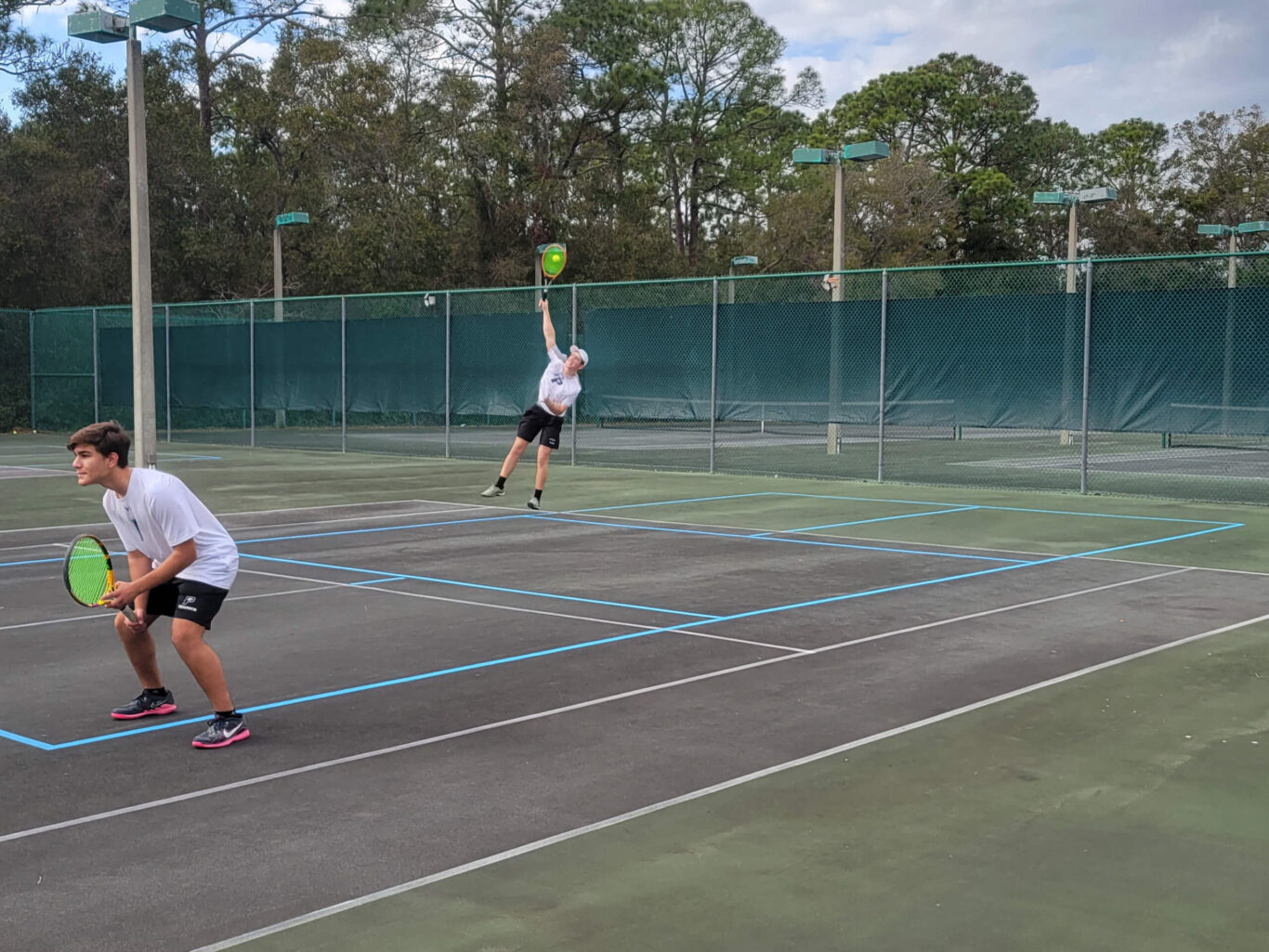 Two boys playing tennis on a tennis court.