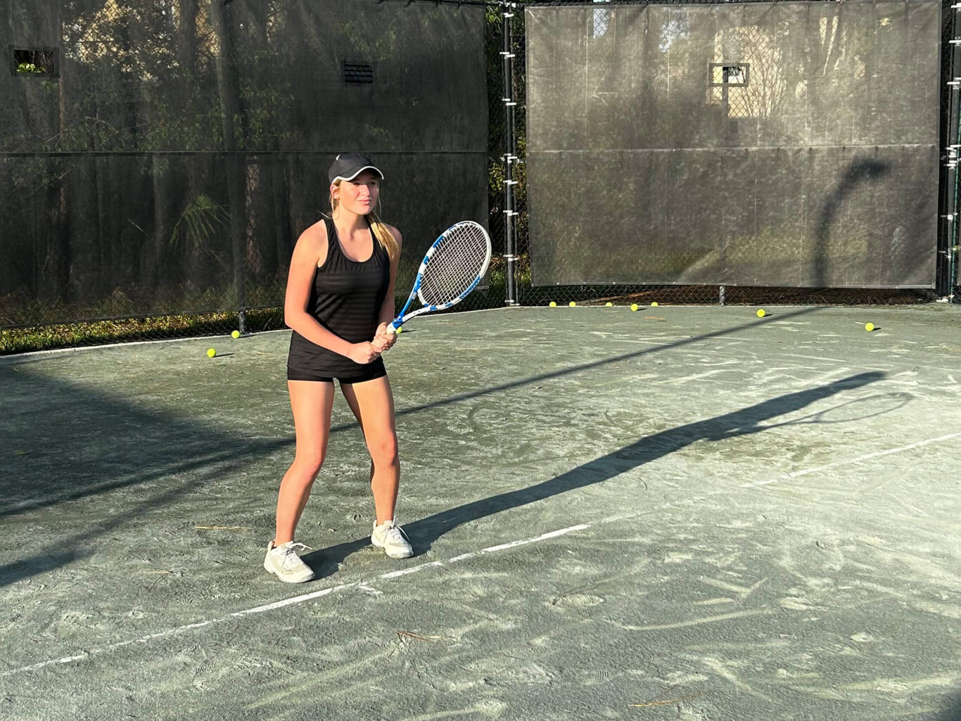 A girl holding a tennis racket on a tennis court.