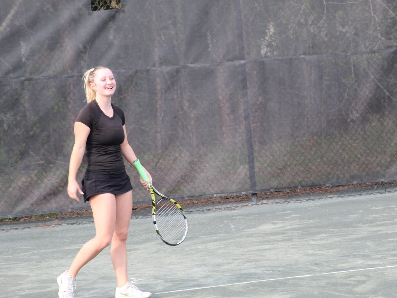 A girl holding a tennis racket on a tennis court.