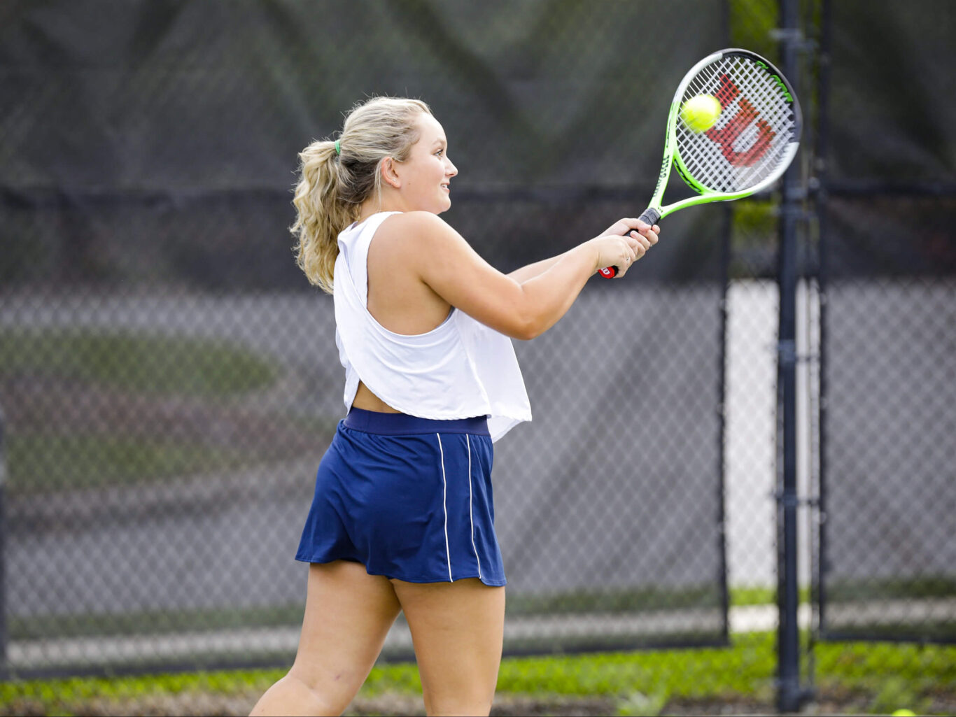 A Tennis Girl swinging a tennis racket at a ball.