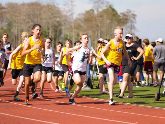 A group of boys running on a track in a Track and Field event.