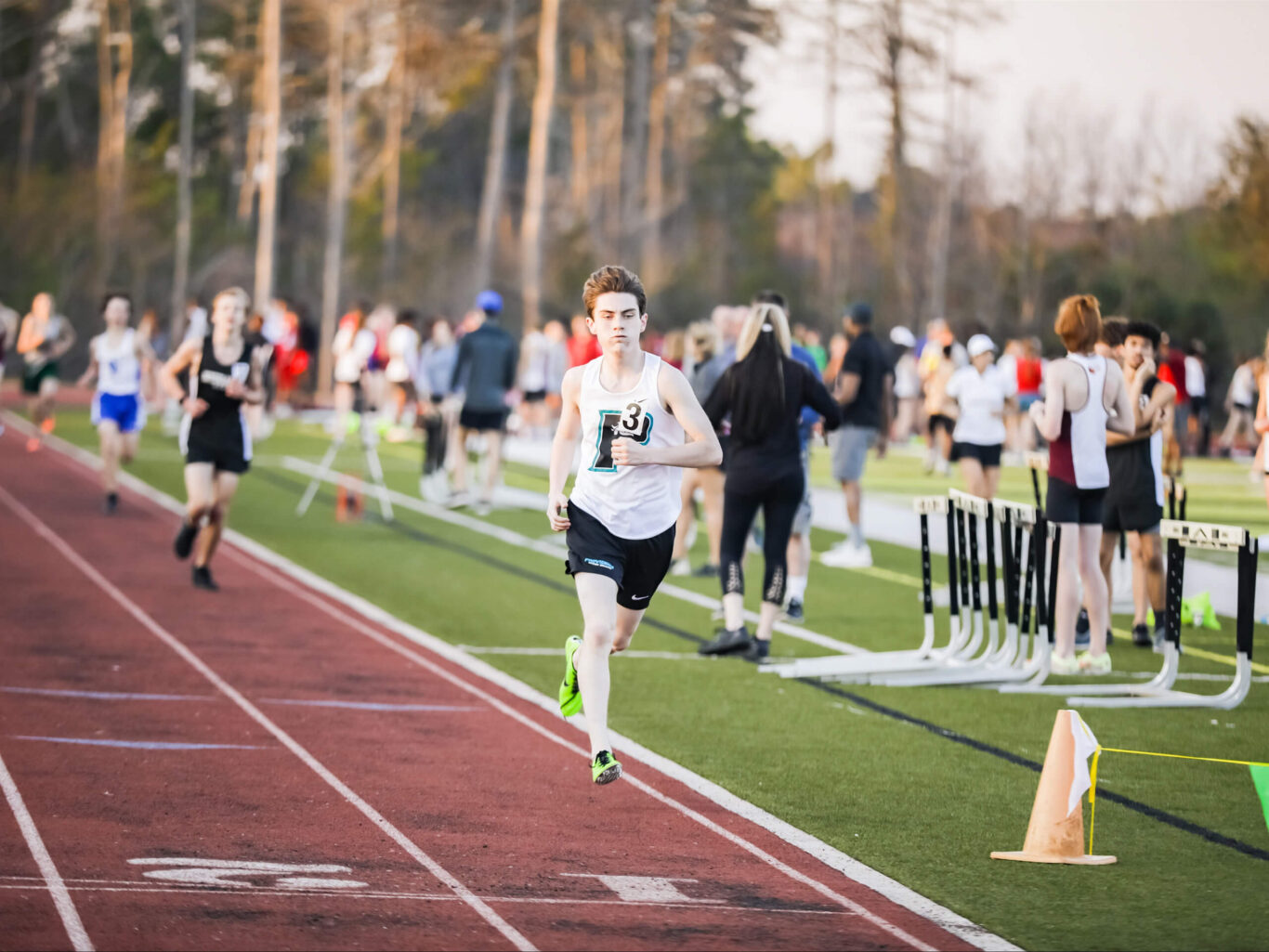 A young man running on a track in front of spectators.