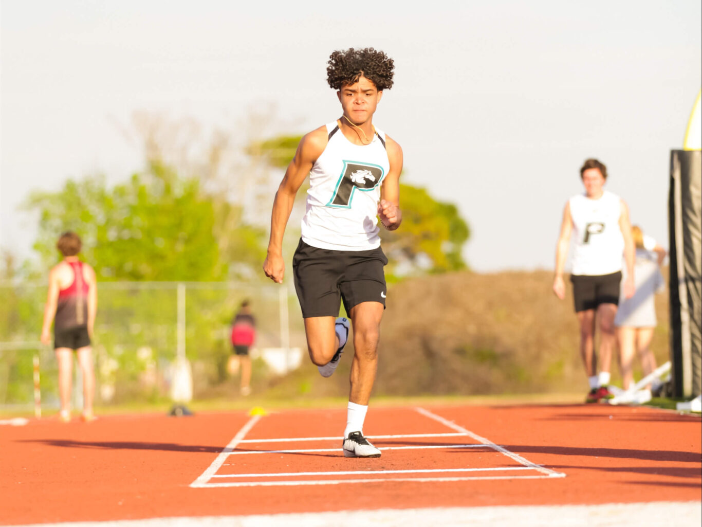 A young man running on a track in a field.
