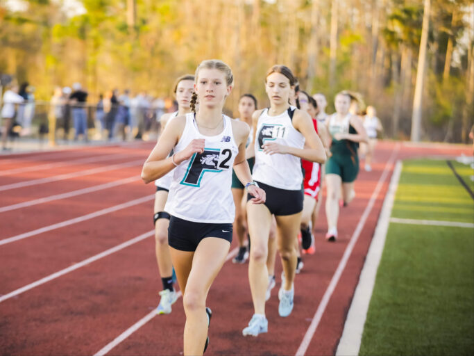 A group of girls sprinting on a track.