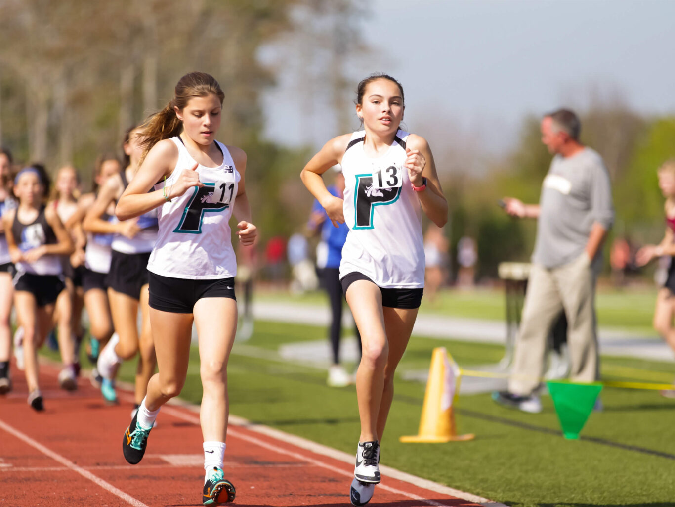 A group of girls participating in track and field events on a track.