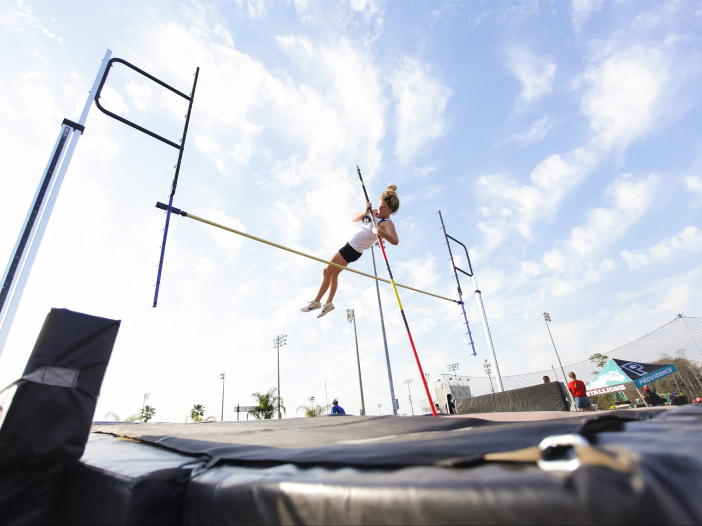 A female high jumper soaring in the air during a track and field event.