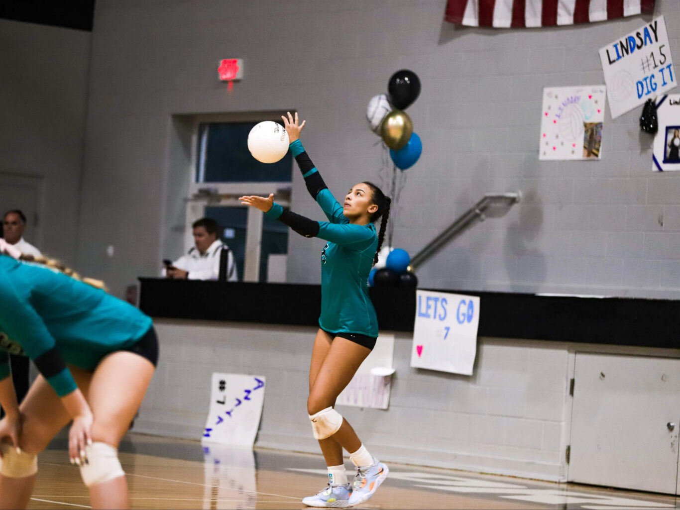 Two girls engaging in a spirited game of volleyball inside a gymnasium.