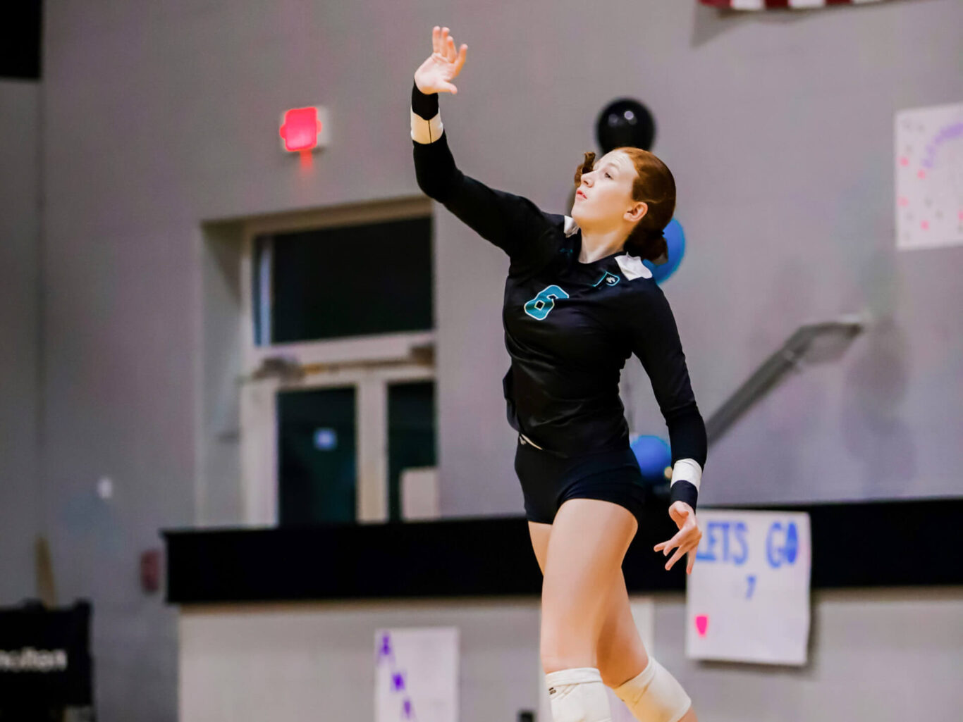 A girls volleyball player is about to hit the ball.