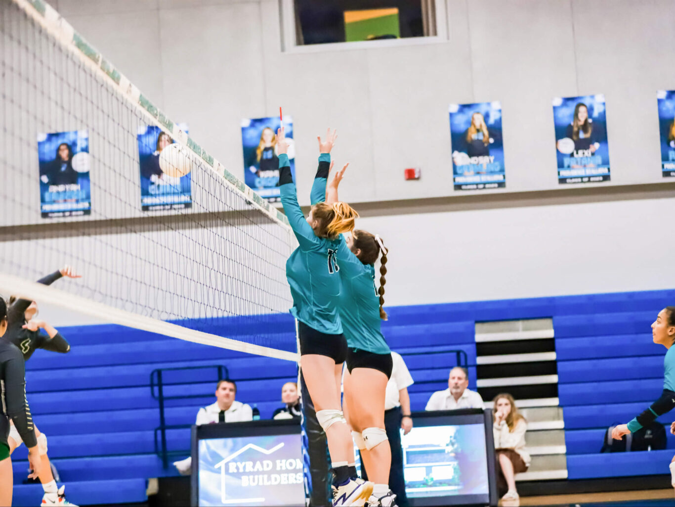 A girls volleyball player is trying to hit the ball.
