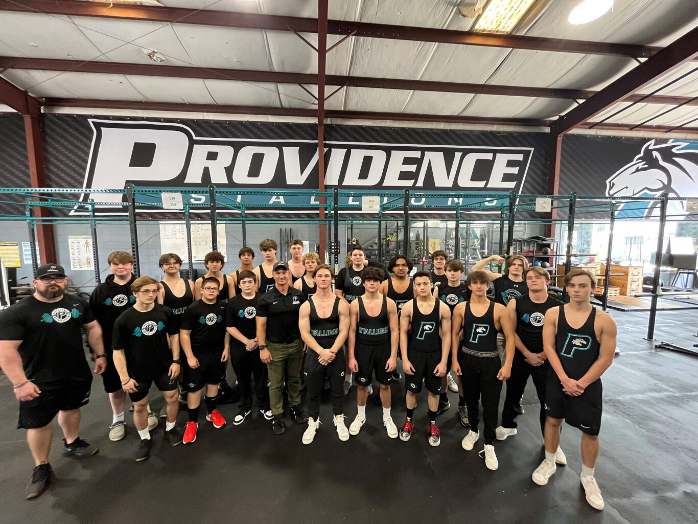 A group of boys weightlifting in a gym while posing for a photo.