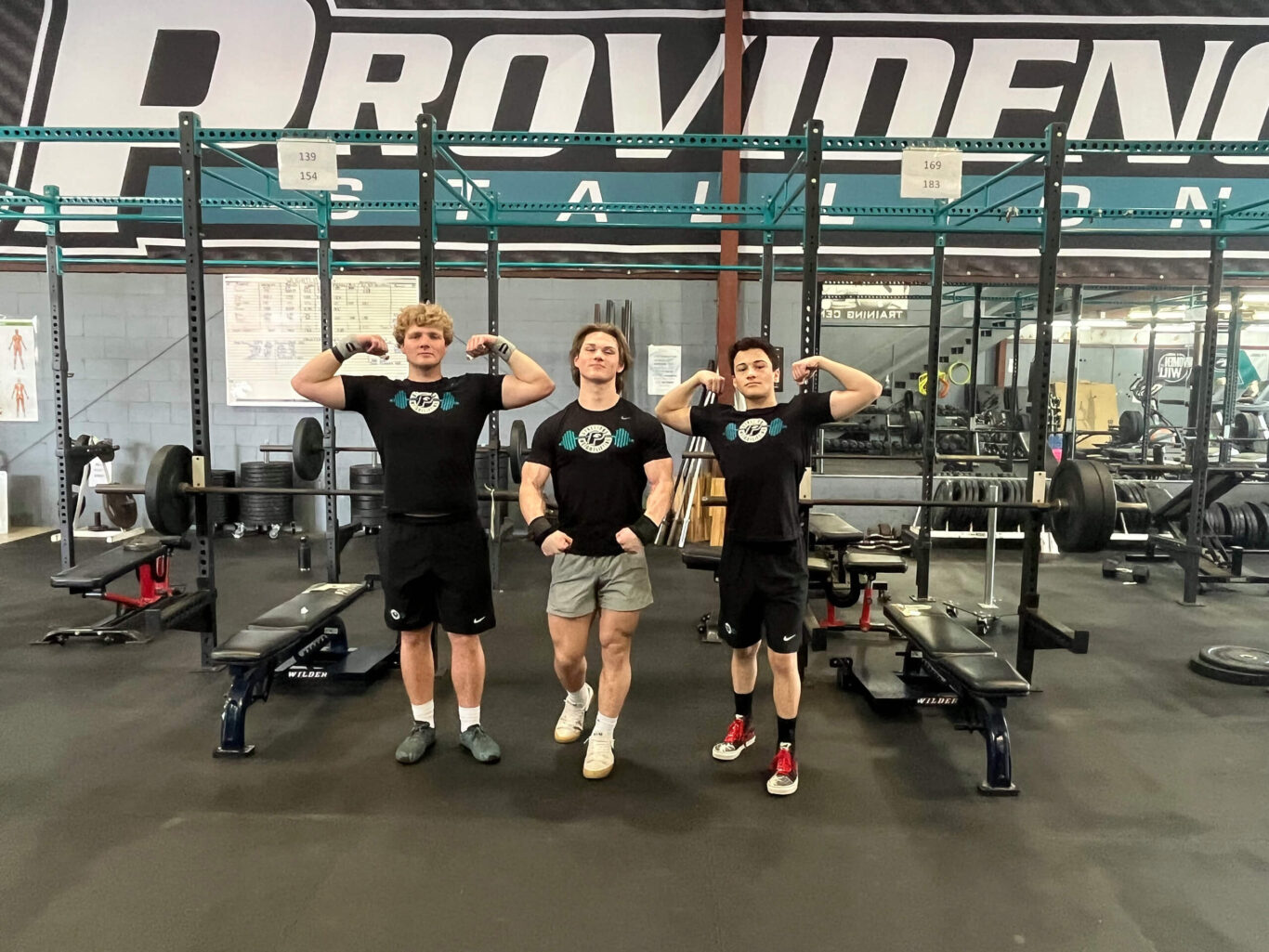 Three young boys posing for a photo in a gym.