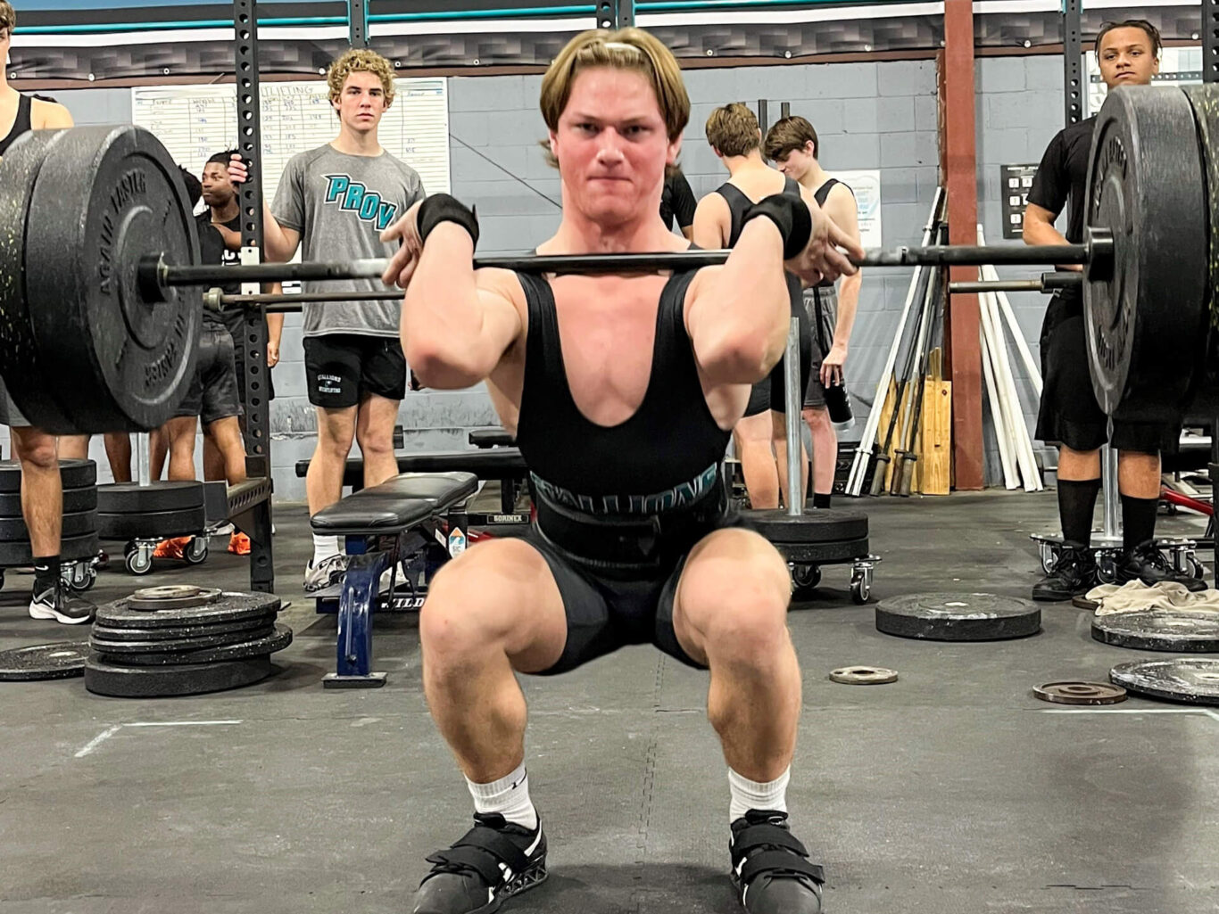 A man weightlifting with a barbell in front of him.