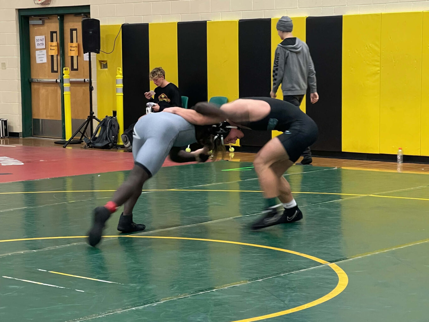 Two boys are wrestling in a gym.