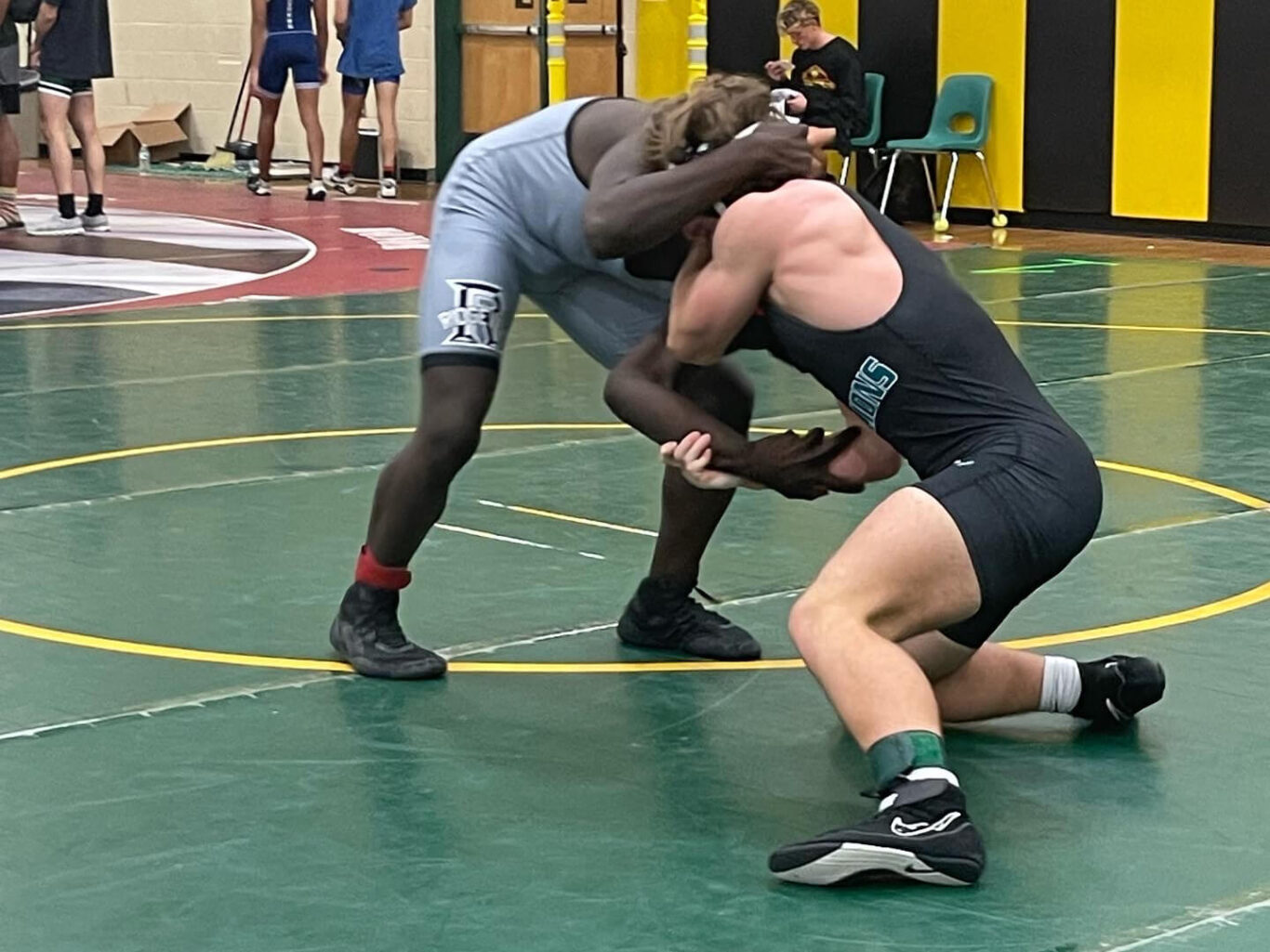 Two boys wrestling in a gym.