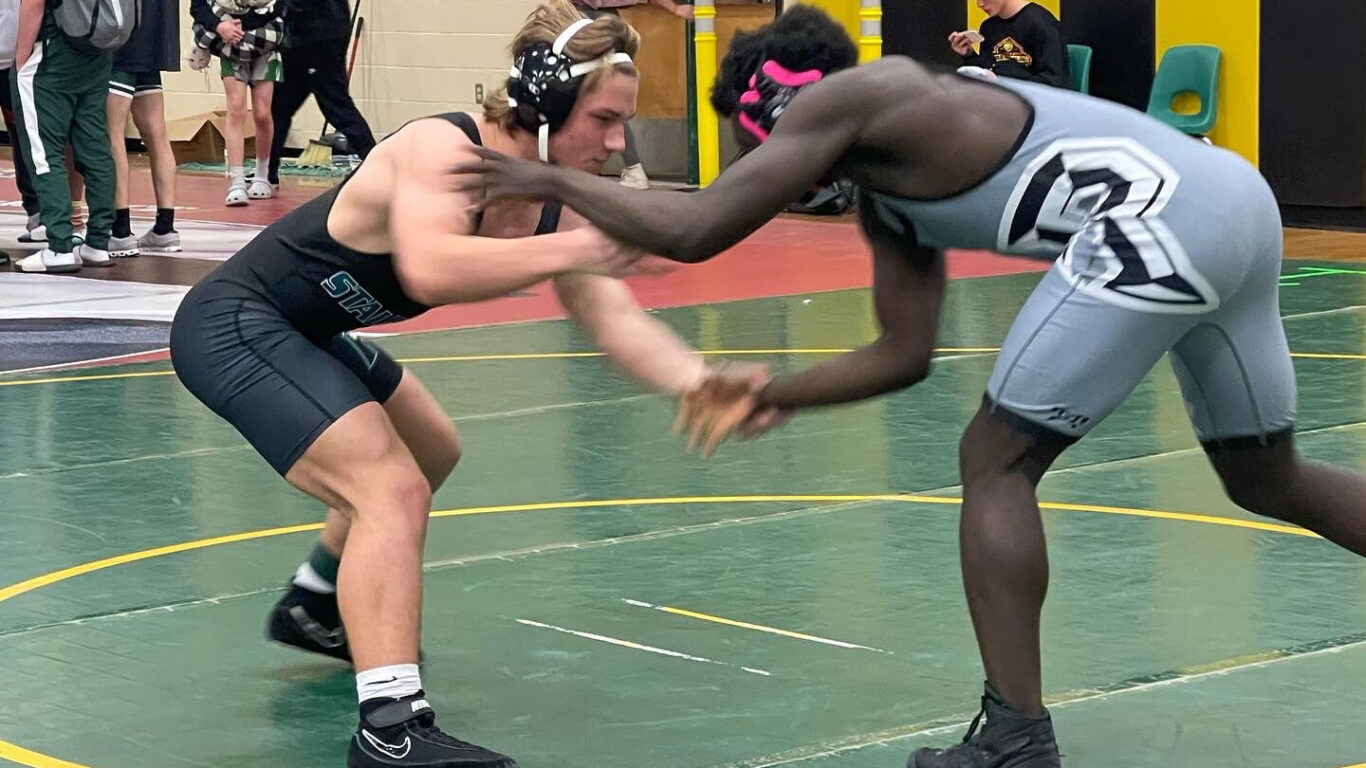 Two boys wrestling in a wrestling match.