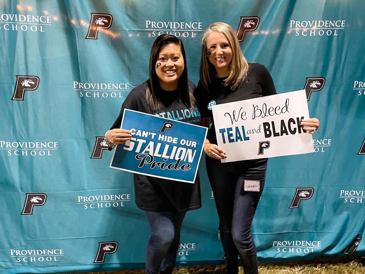 Two women standing in front of a banner that says real black at Homecoming 2023.